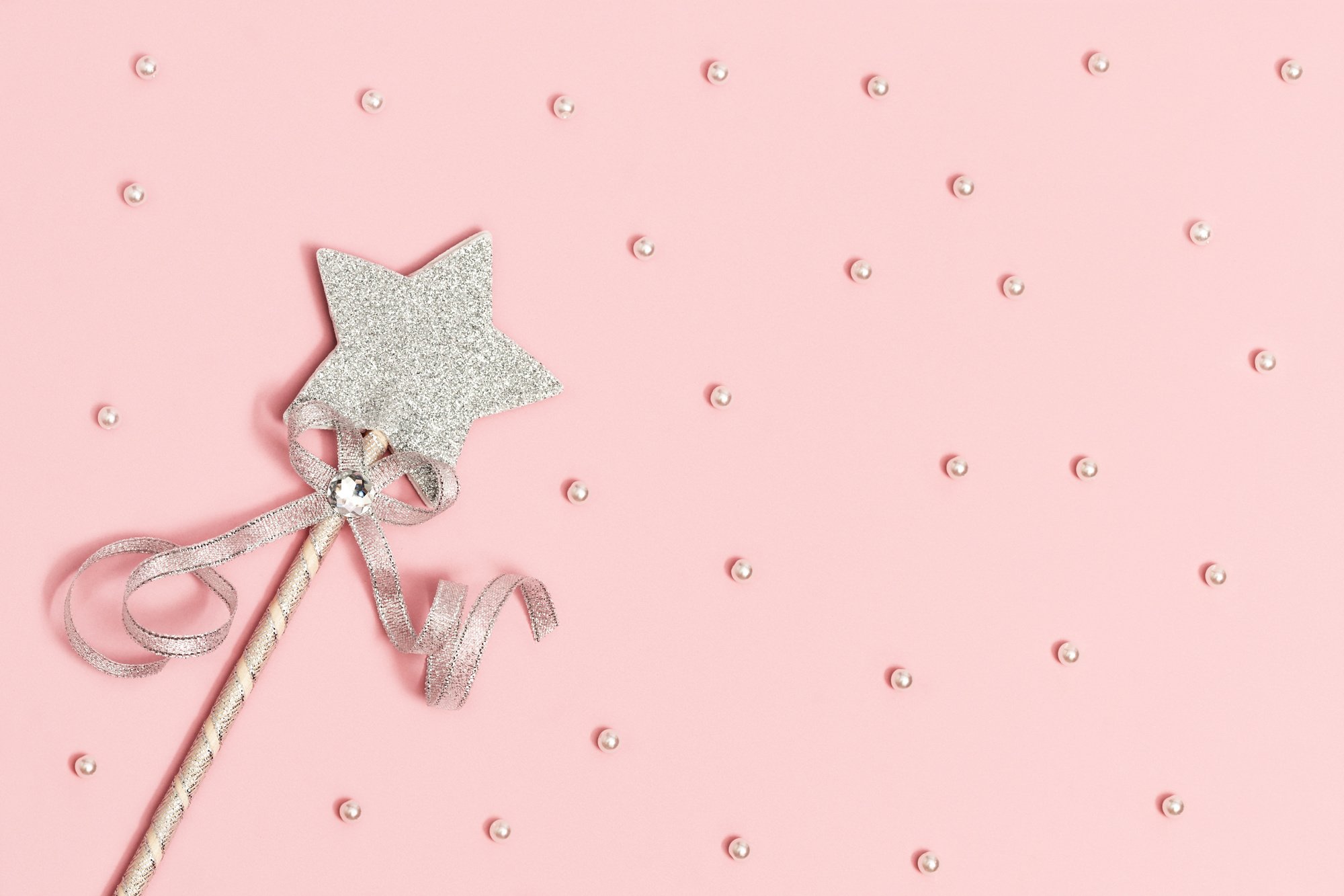 Festive decoration, bright silver star with sequins on soft pink background with white beads. Minimal holiday concept. Flat lay.